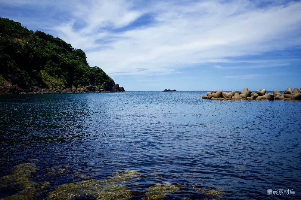 高清摄影  在白天，蓝蓝的大海下，白云飘浮在蓝天之间，形成了一道绿色和棕色的岩石景观。