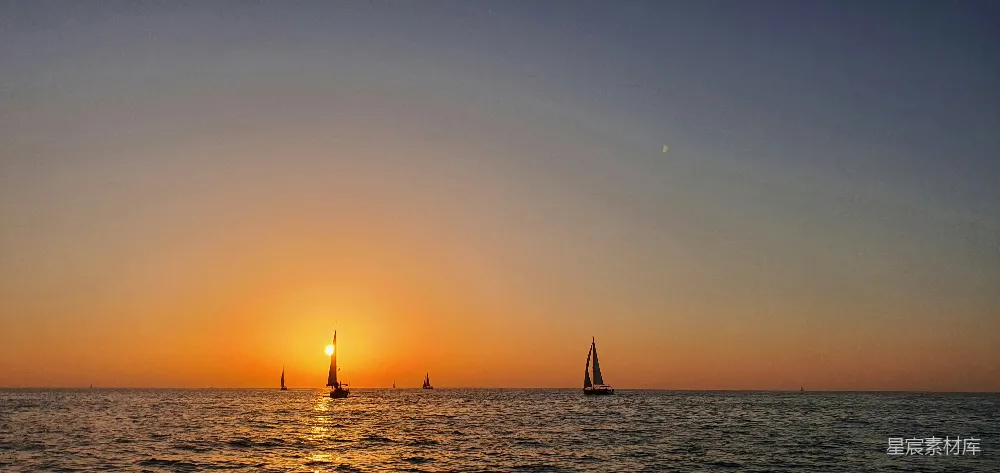 高清摄影  夕阳西下时海面上帆船的剪影