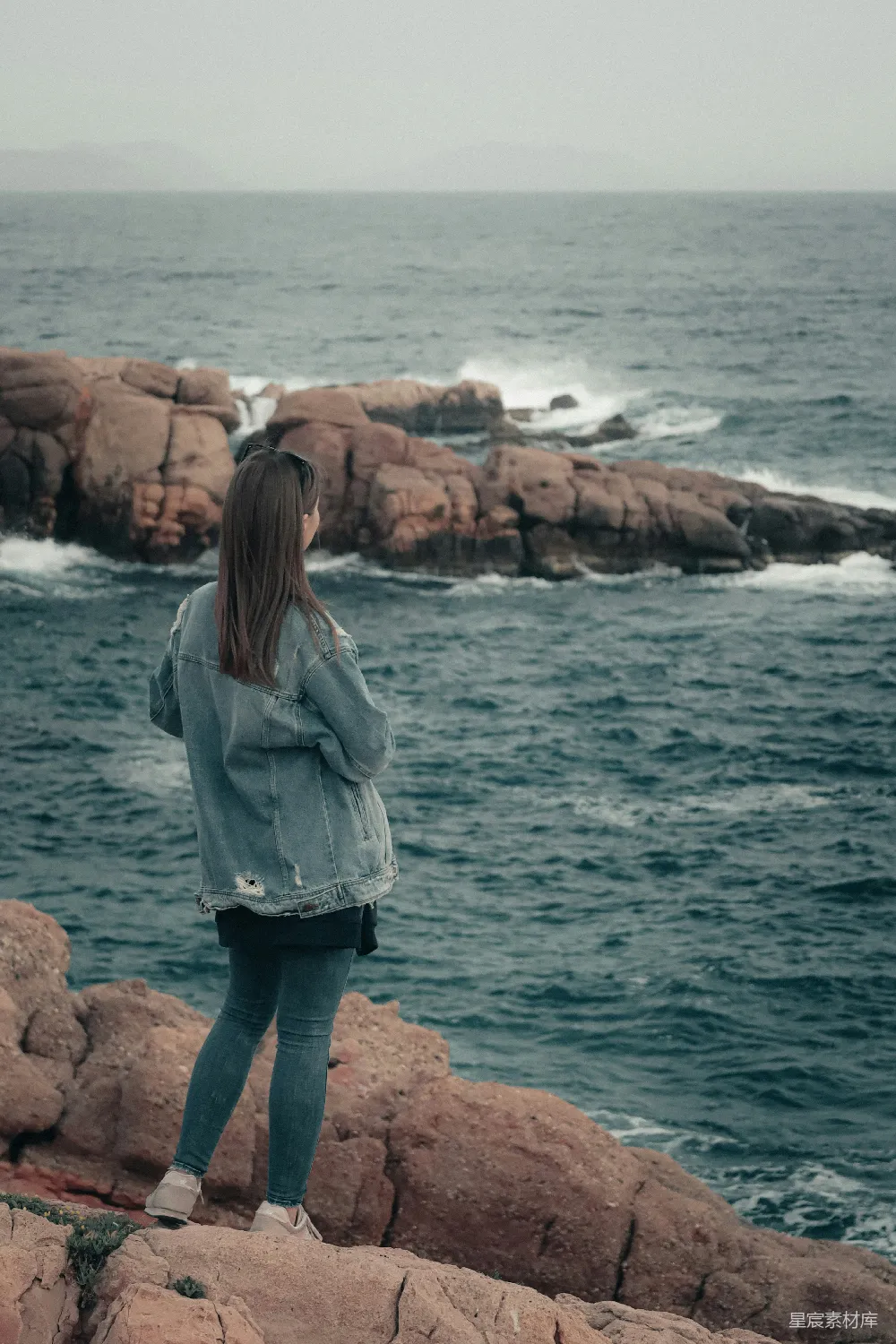 高清摄影 人物 旅行 一位站在岩石海岸边的女性，她靠近大海。