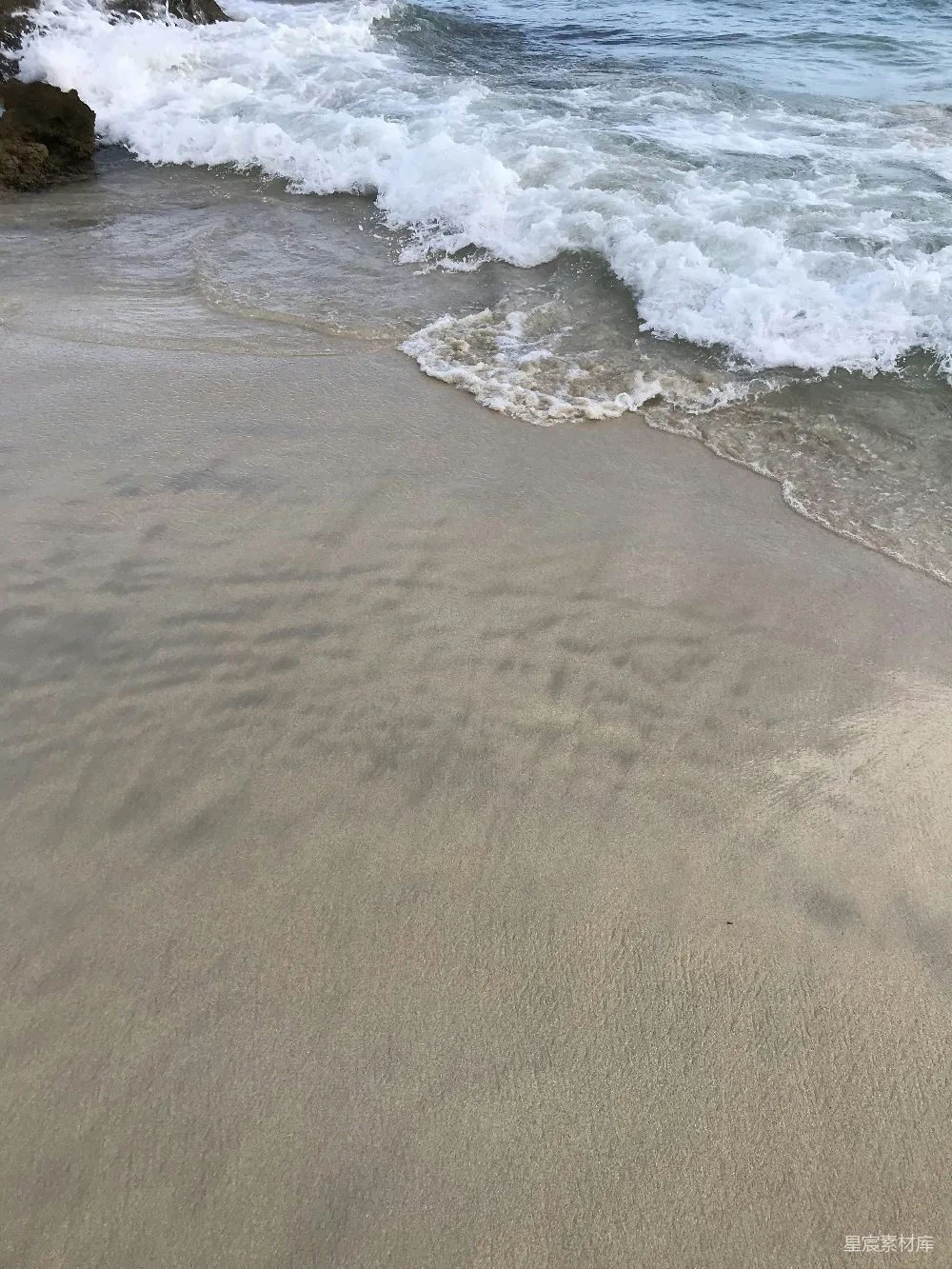 高清摄影  沙滩紧邻大海，海浪不断涌来。