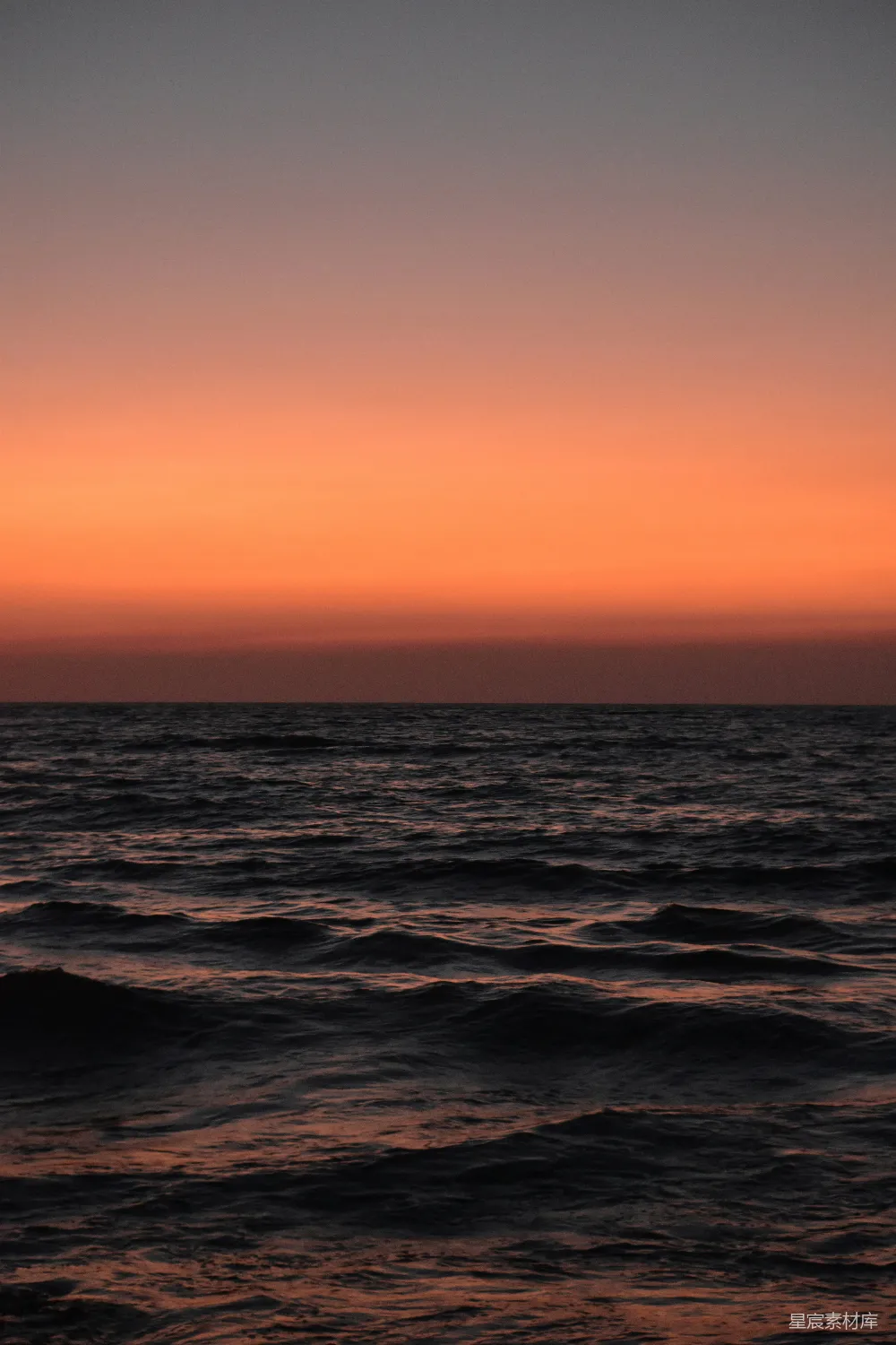 高清摄影  在色彩斑斓的橙色夕阳下，海浪轻轻拍打。