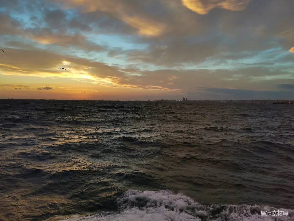 高清摄影  夕阳正缓缓落下，海面上有一艘船在远处航行。