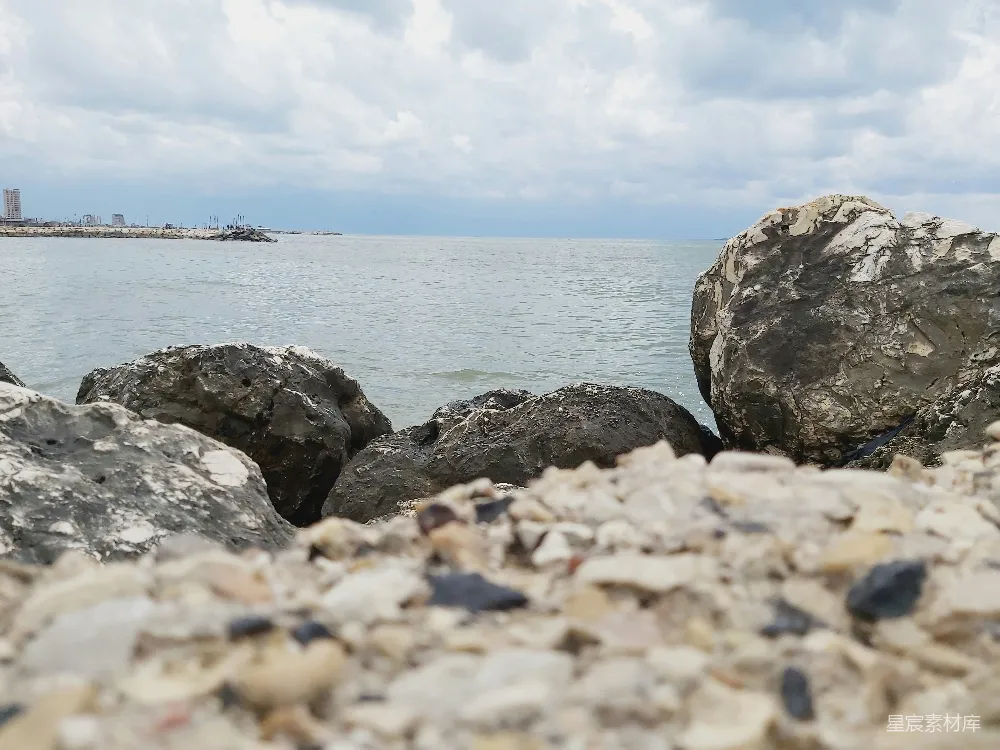 高清摄影  一块岩石海滩，背景中有一片水域。