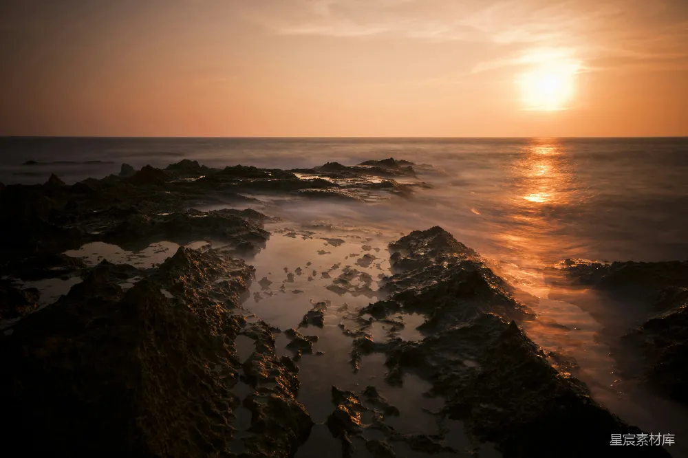 高清摄影  海边的黑色岩石在夕阳下显得格外醒目。