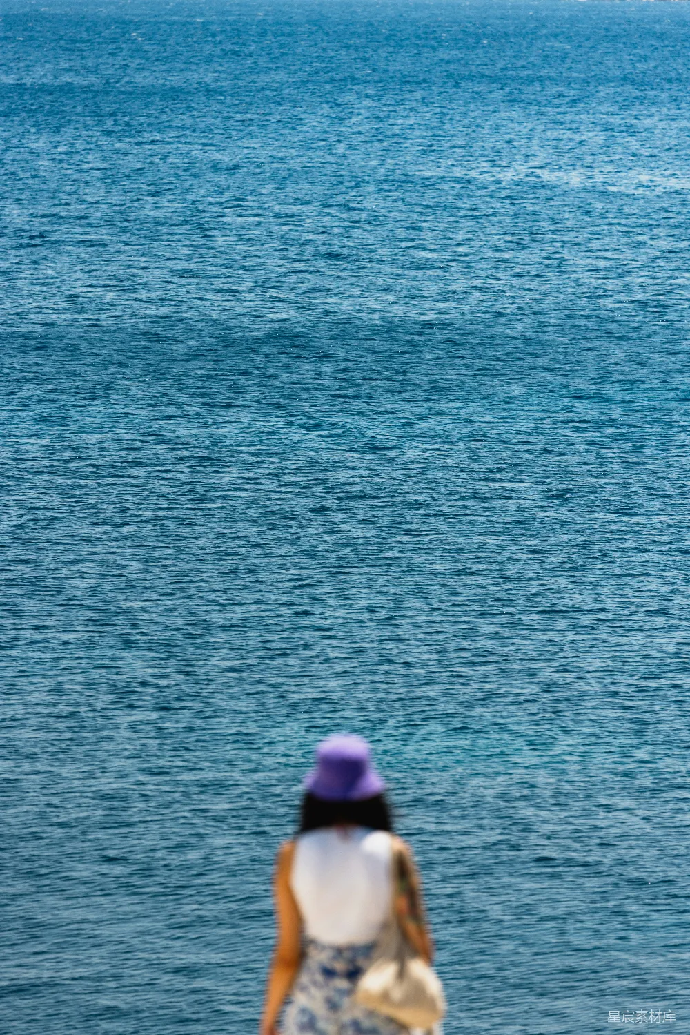 高清摄影  一个女人在海滩上沿着海边散步。