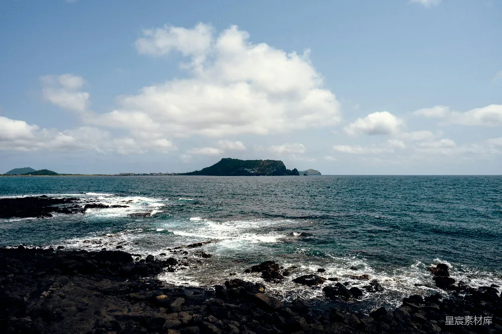 高清摄影  一个岩石海滩，背景中有一大片水域。