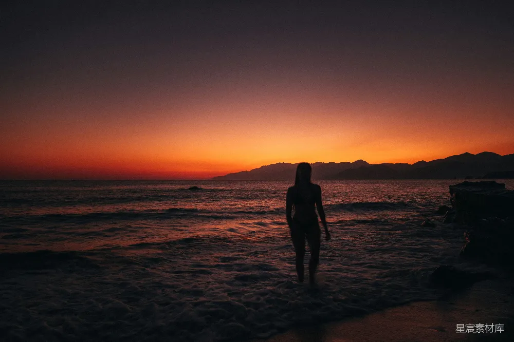 高清摄影  一对男女站在海滩上，夕阳下剪影。