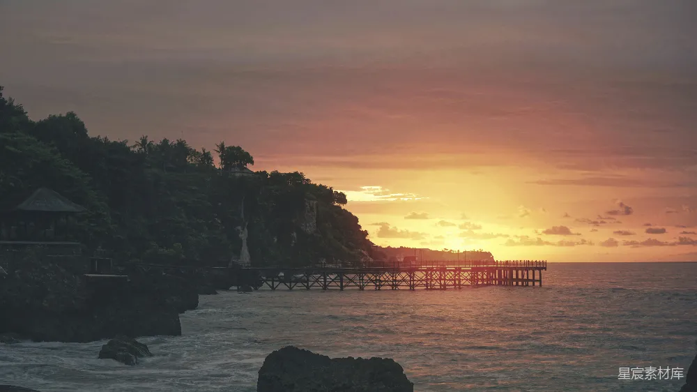 高清摄影  夕阳映照在海面上，木制码头延伸出去。