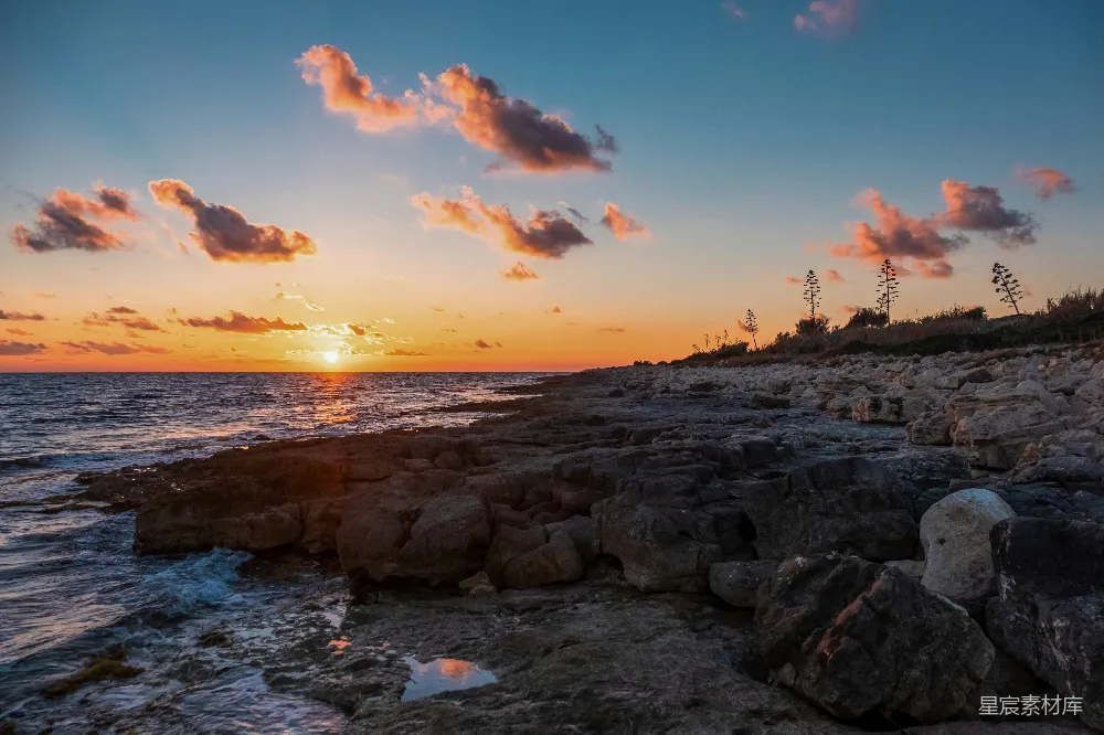 高清摄影  夕阳正缓缓落下，照耀着岩石海岸。