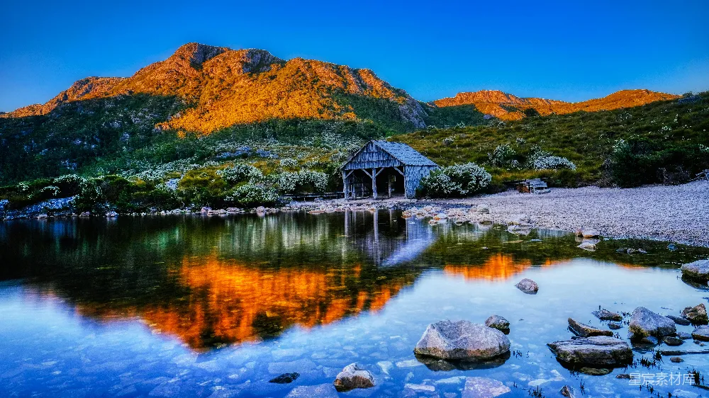 高清摄影  湖边棕色的木屋在蓝天下的白天，旁边是棕色的山。