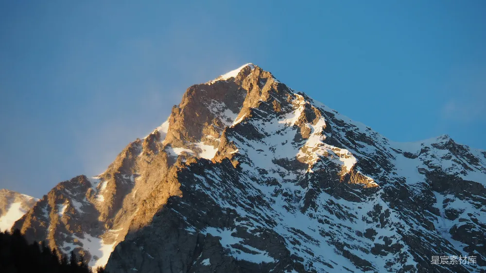 高清摄影  一座被雪覆盖的山峰，背景是蓝天。