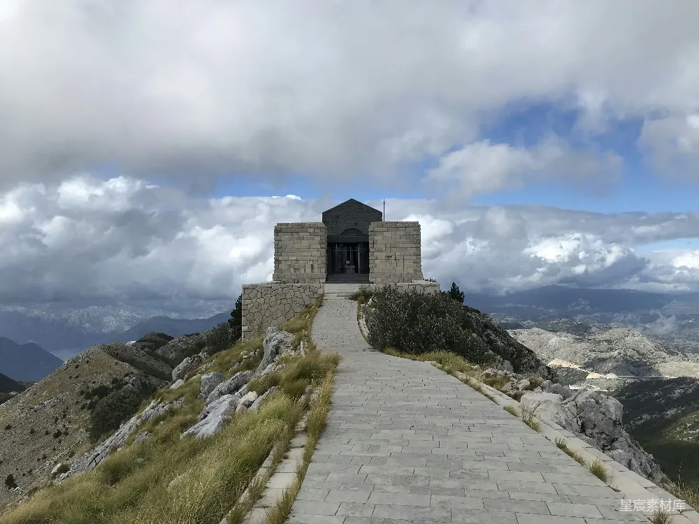高清摄影  白天，多云的天空下，一座灰色的混凝土建筑位于山丘之巅。