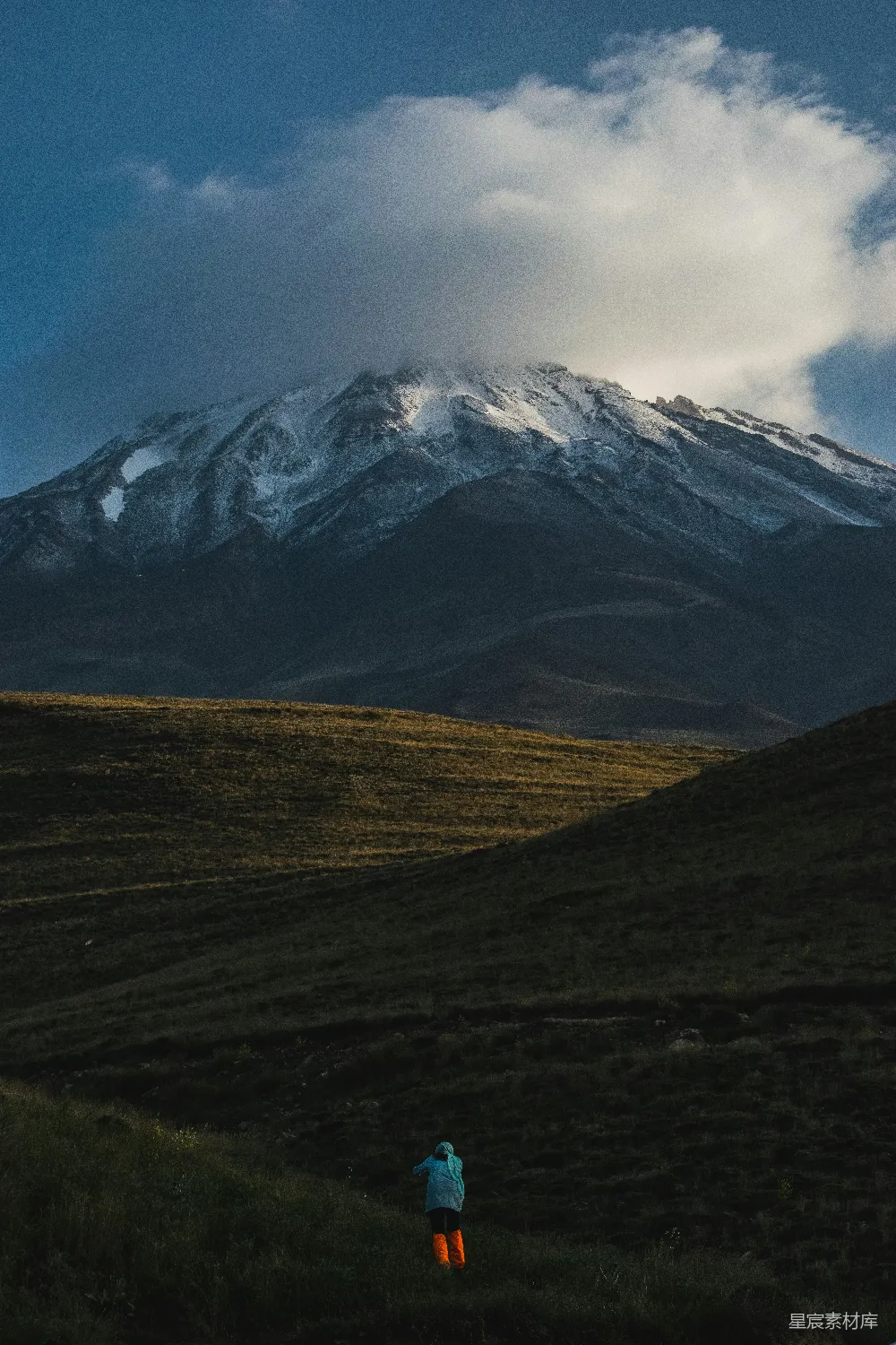 高清摄影  一个人站在田野里，背景是山脉。