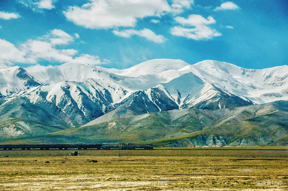 高清摄影  一辆火车穿越乡村，背景是群山。
