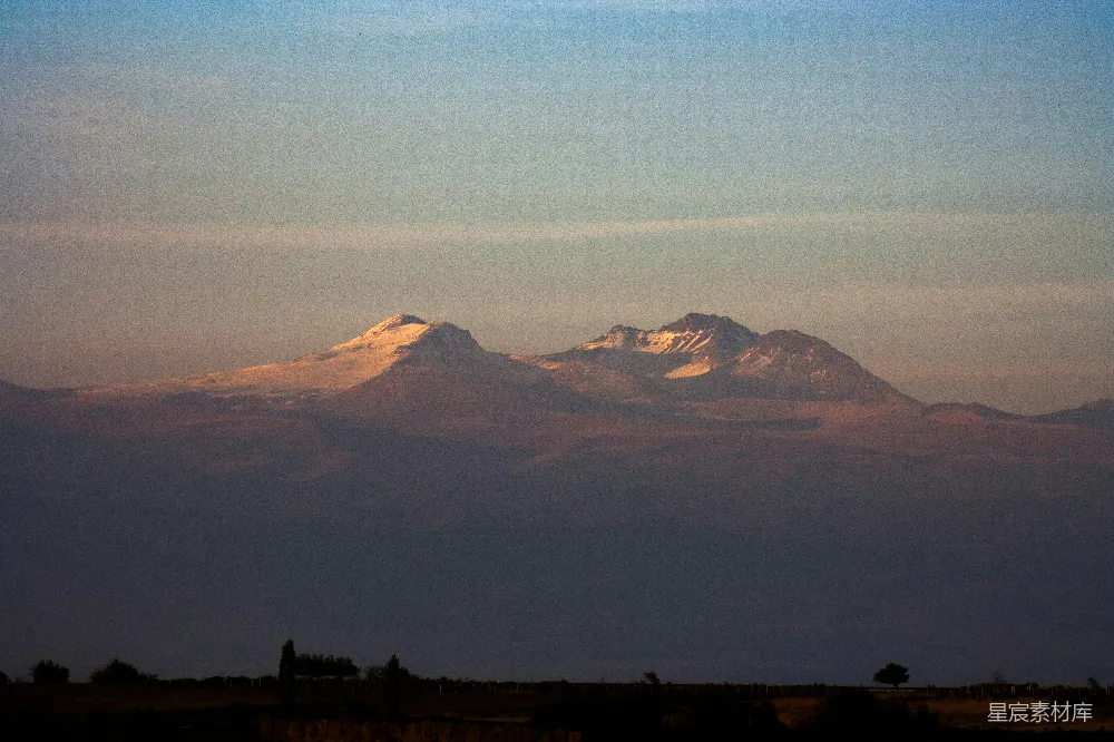 高清摄影  夕阳下白雪覆盖的山峰，隐约可见轮廓。