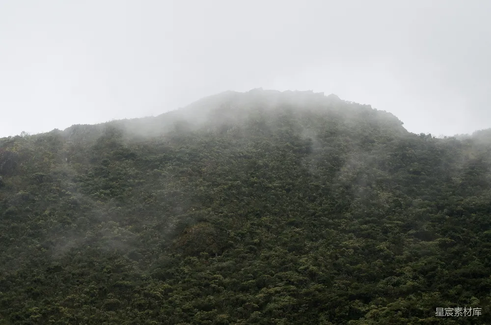 高清摄影  一座高耸入云的山峰，笼罩在雾气和云层之中。