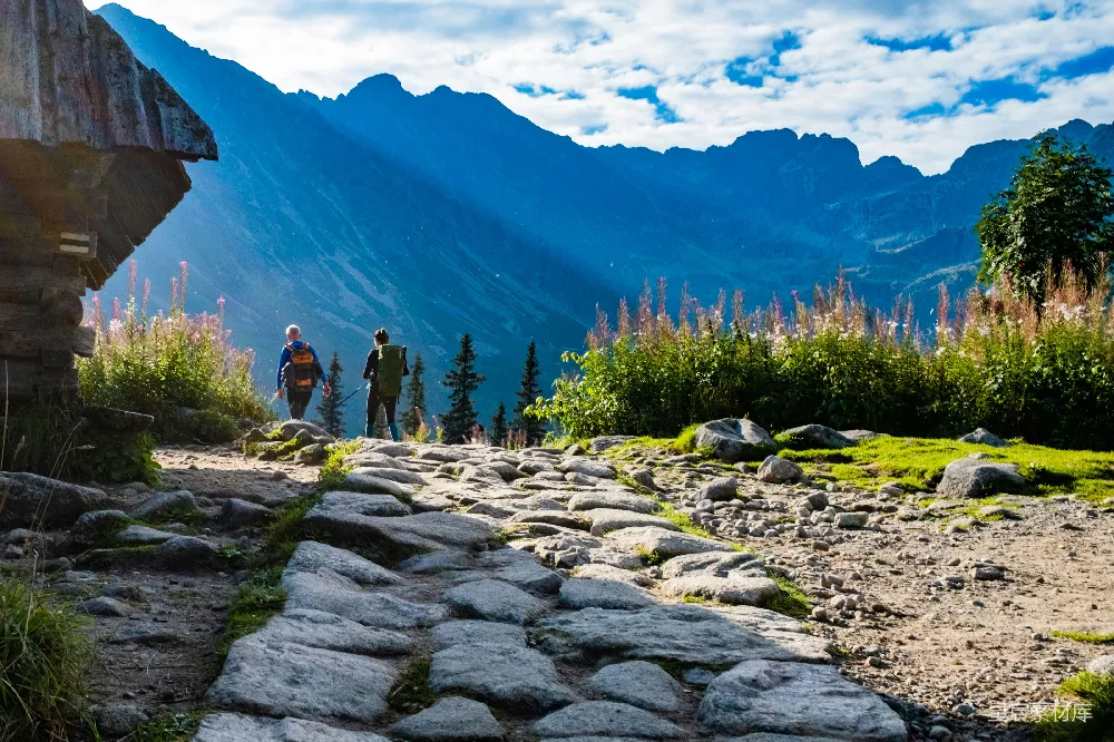 高清摄影  一群人在岩石小路上，面前是一座山。