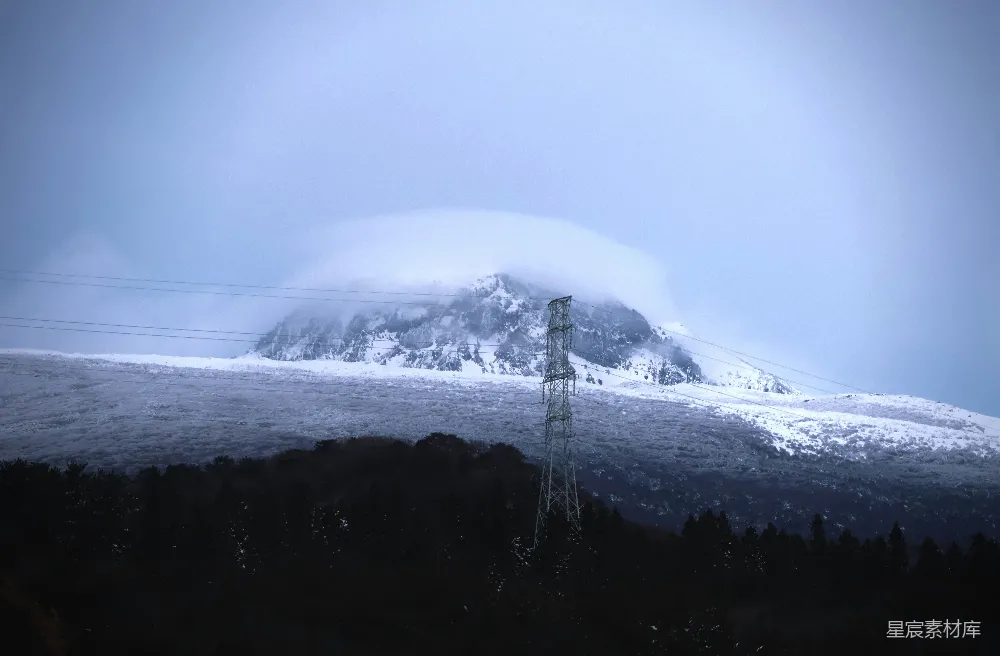 高清摄影  一座覆盖着积雪的山，前景中有一根电线杆。