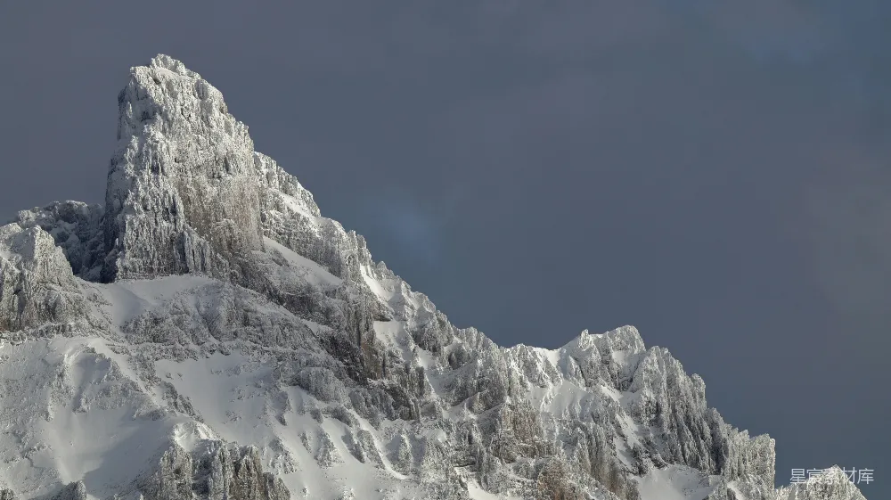 高清摄影  被白雪覆盖的崎岖山峰在黑暗的天空下