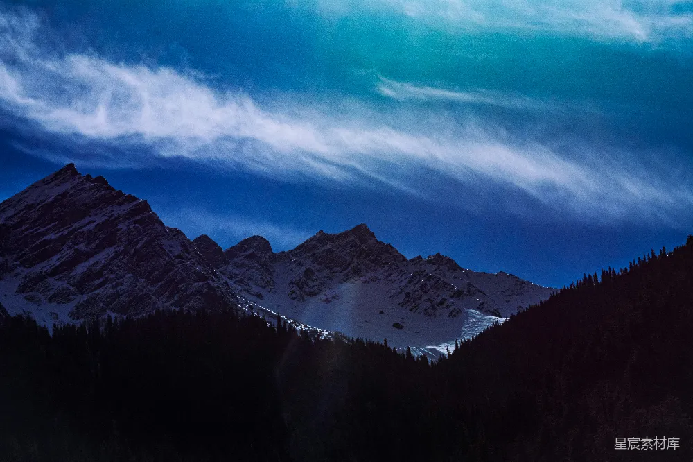 高清摄影  一座山峦连绵的景观，前景中有树木。