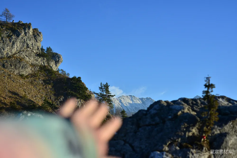 高清摄影  一只手伸向背景是蓝天的山峰。