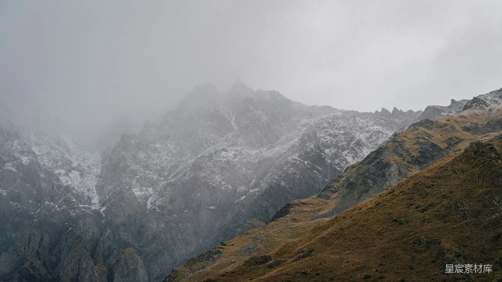 高清摄影 自然 雾气缭绕的雪山峰顶，覆盖着积雪和干草。