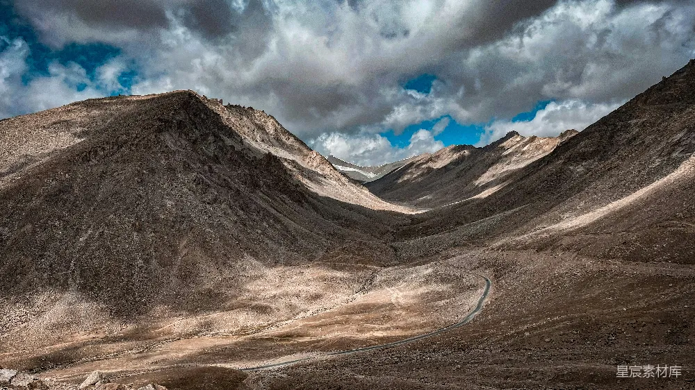 高清摄影  一条蜿蜒的道路在前景中，山峦绵延。