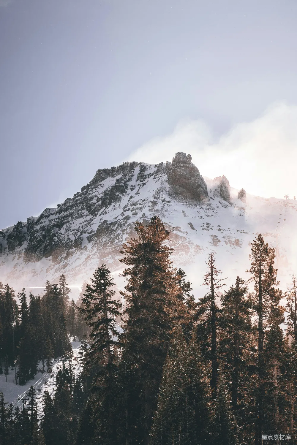 高清摄影  一座被雪覆盖的山，周围环绕着树木。