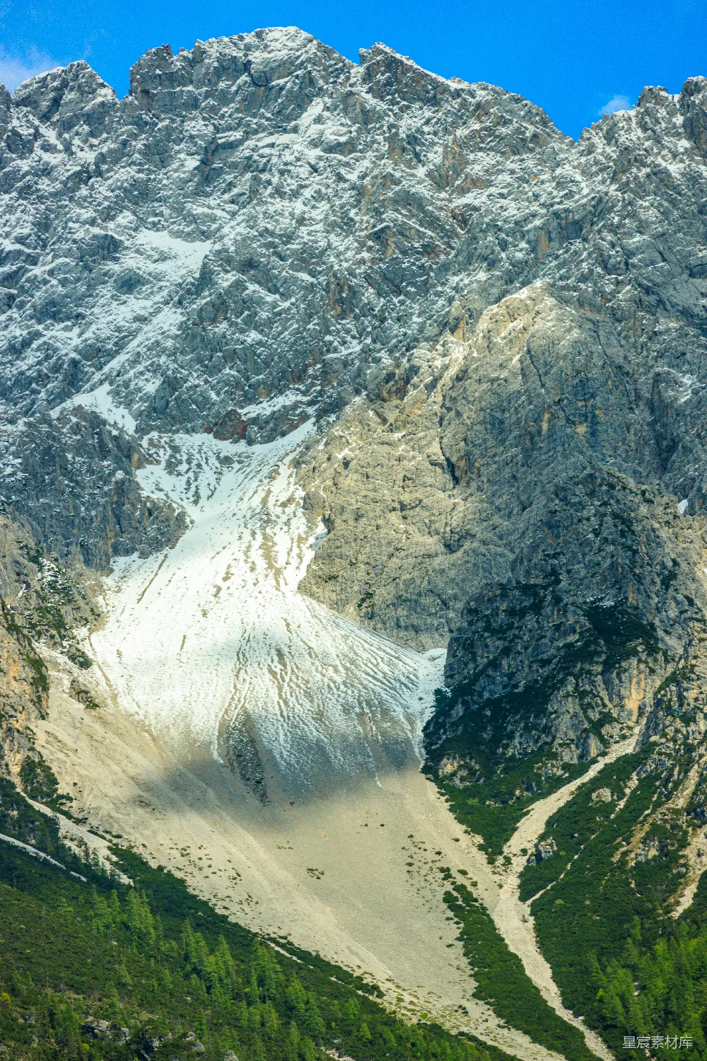 高清摄影  巍峨的岩石山峰，山上有积雪和绿树。