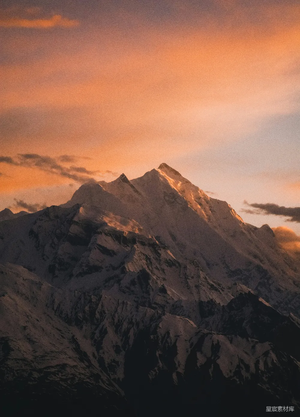 高清摄影  被美丽的橙色日落照亮的雪山峰顶。