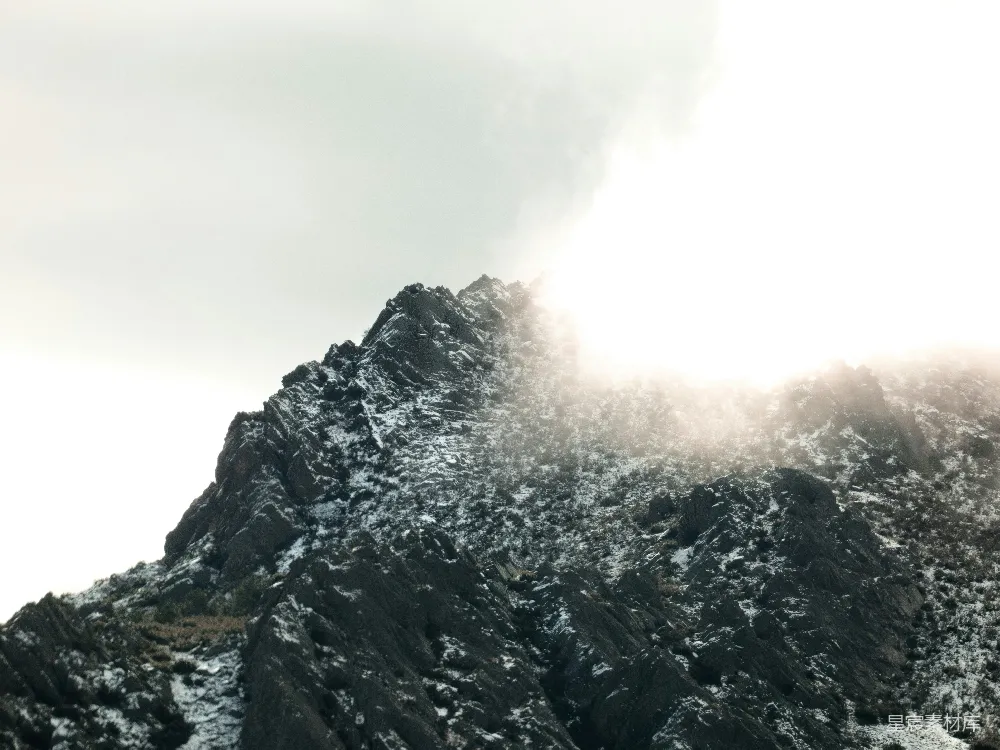 高清摄影  雪山顶峰部分被明亮的云层遮挡。