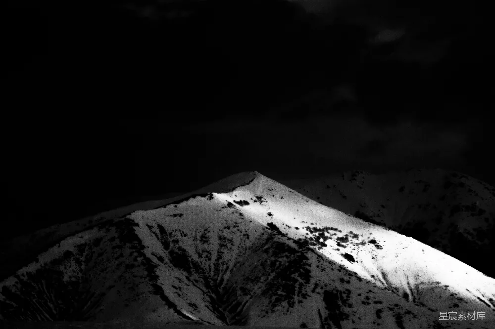 高清摄影  一座在黑暗天空下的白雪覆盖的山峰。