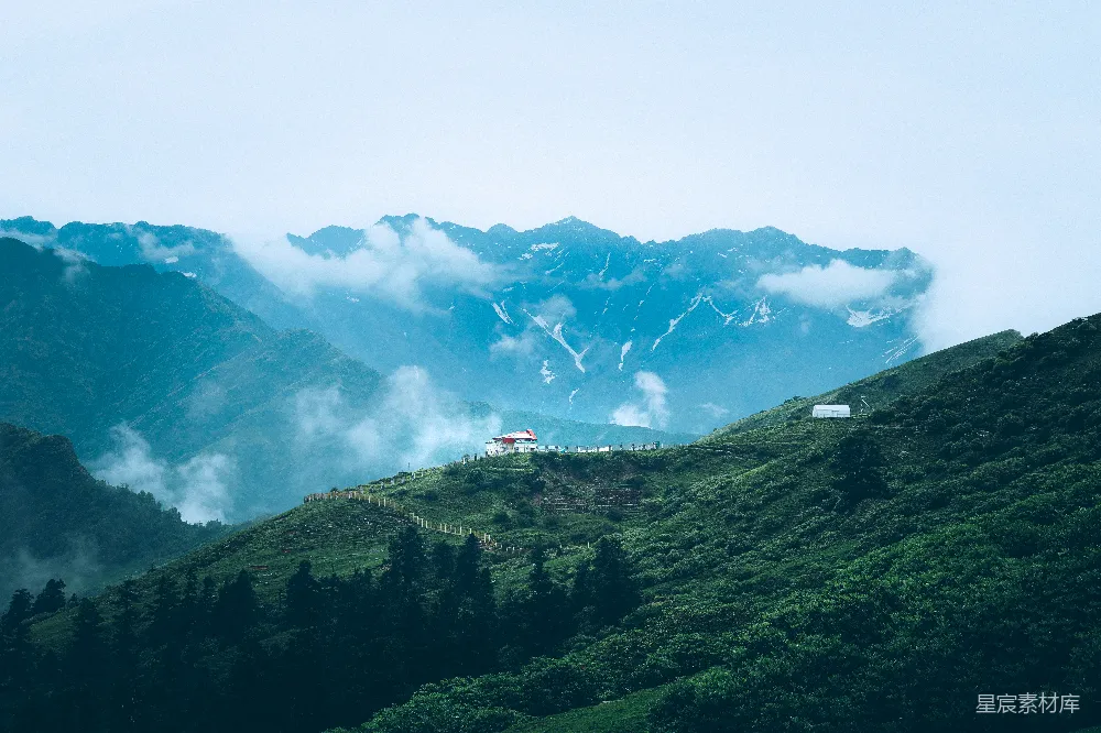 高清摄影  雾气缭绕的山峦，绿意盎然的山丘和散布其中的白色建筑。