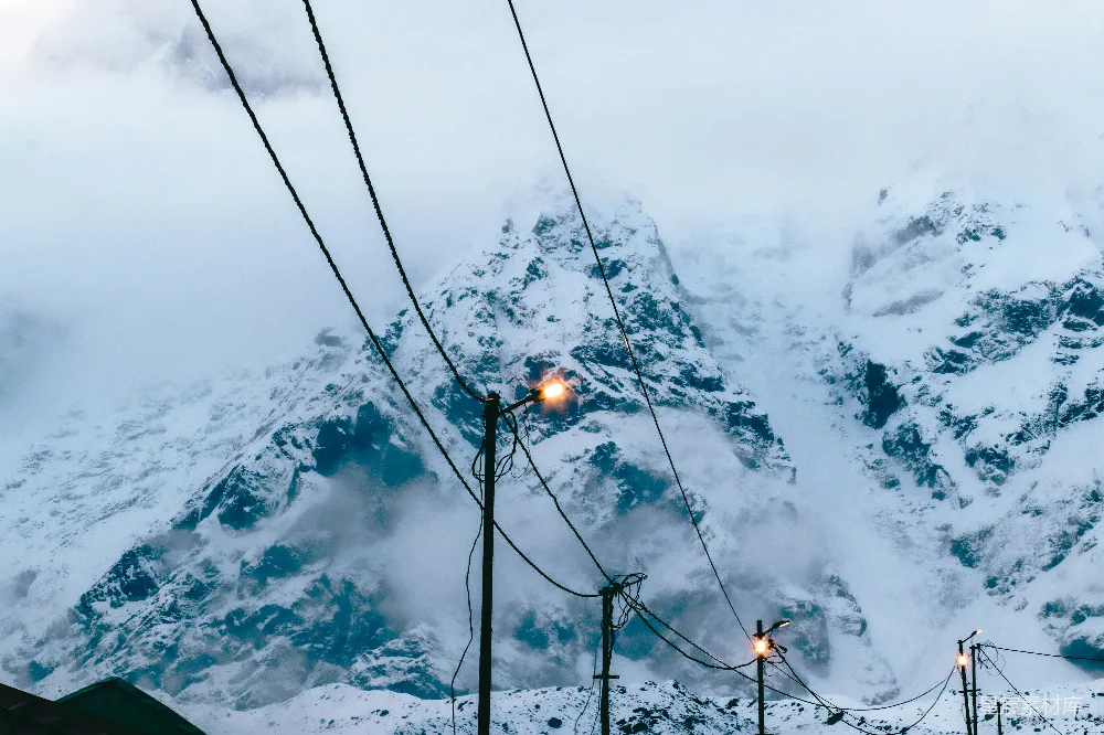高清摄影  一座覆盖着积雪的山，街道上亮着路灯。