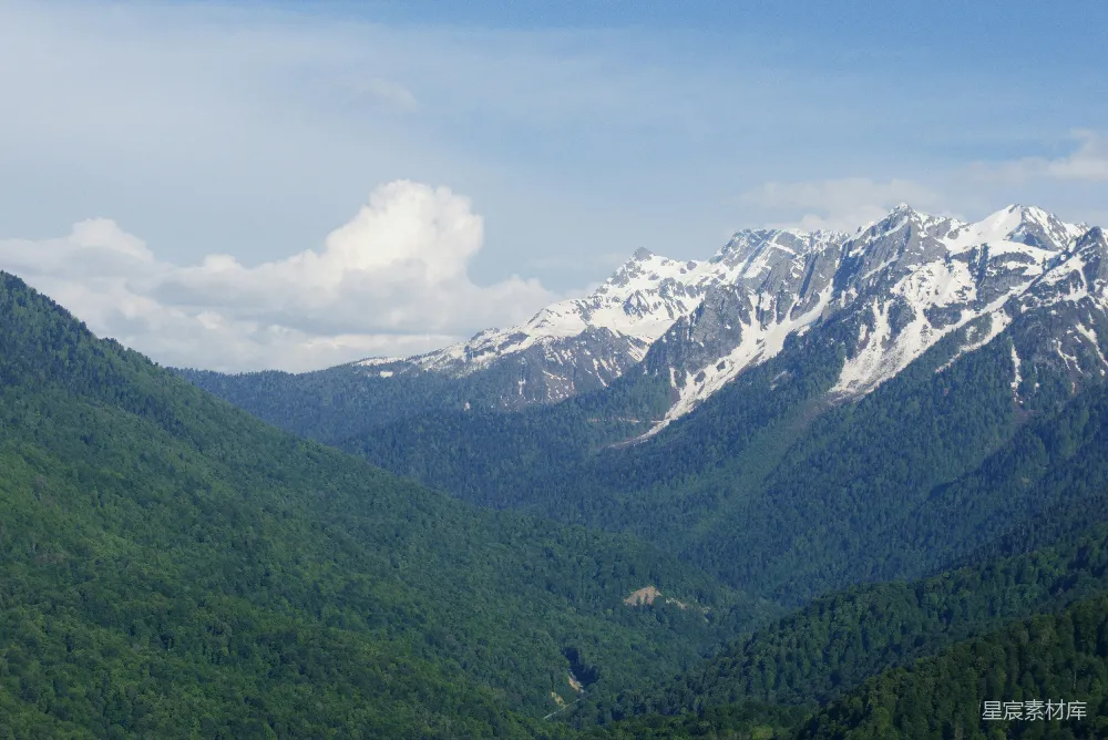 高清摄影  雪山覆盖的山脉俯瞰着一片广阔的绿意盎然的山谷。