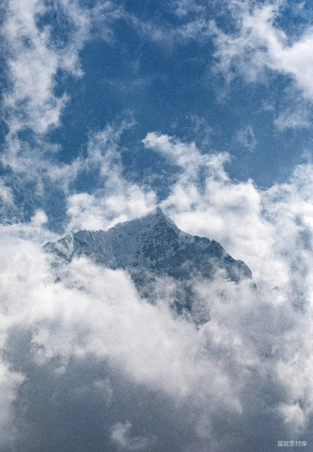 高清摄影  一座被云雾笼罩的高山，在蓝天之下。
