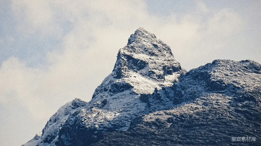 高清摄影  白天，云层密布的天空下覆盖着积雪的山峰。