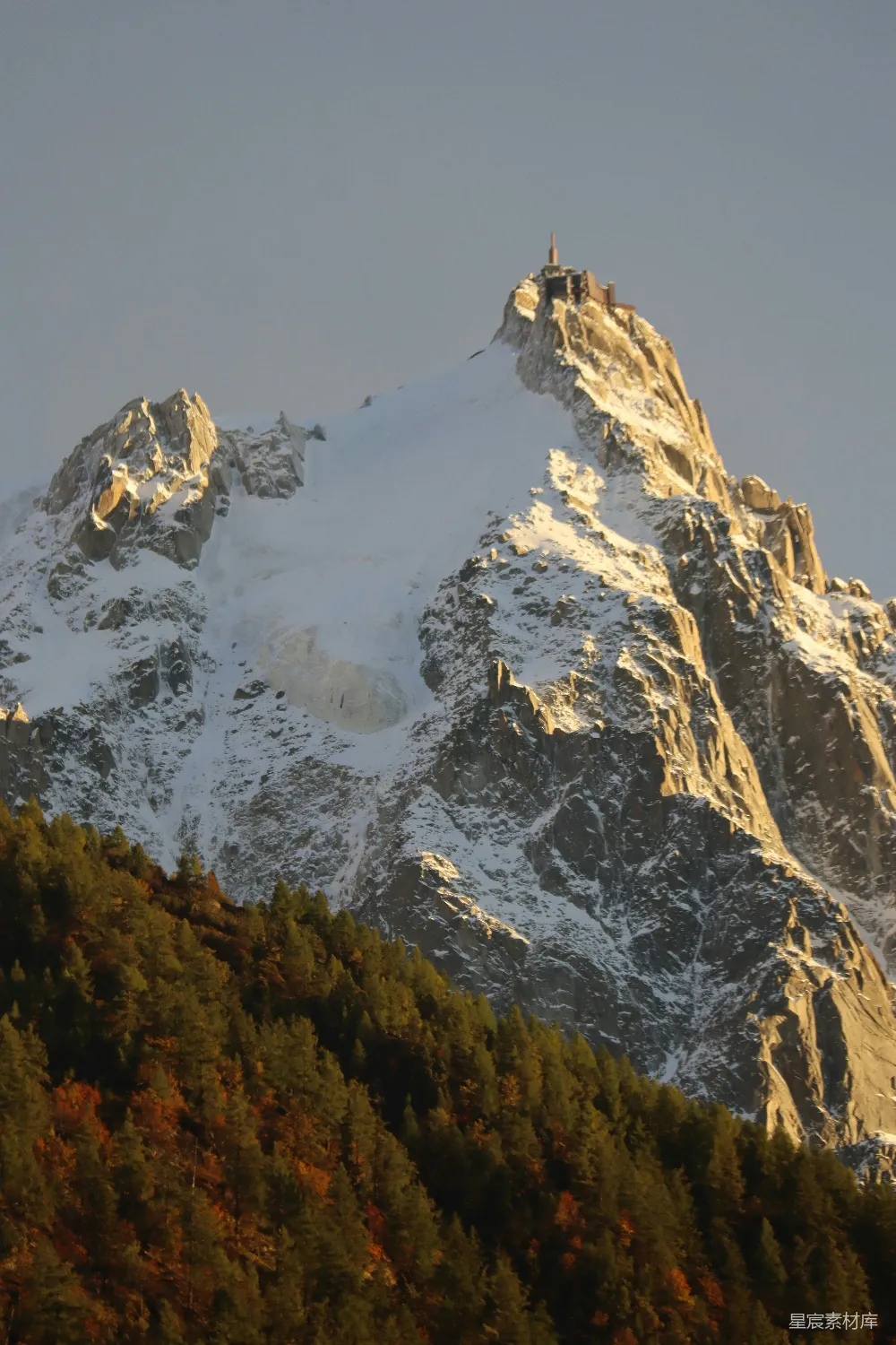 高清摄影  白雪覆盖的山峰，下方有一片松树林。