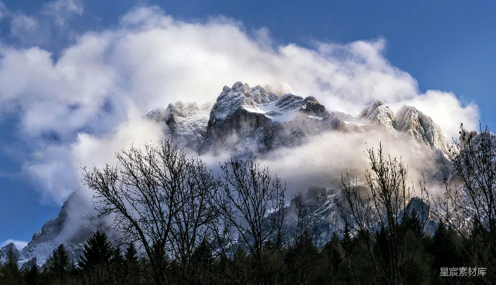 高清摄影  被云雾缭绕的雪山和下面的森林。
