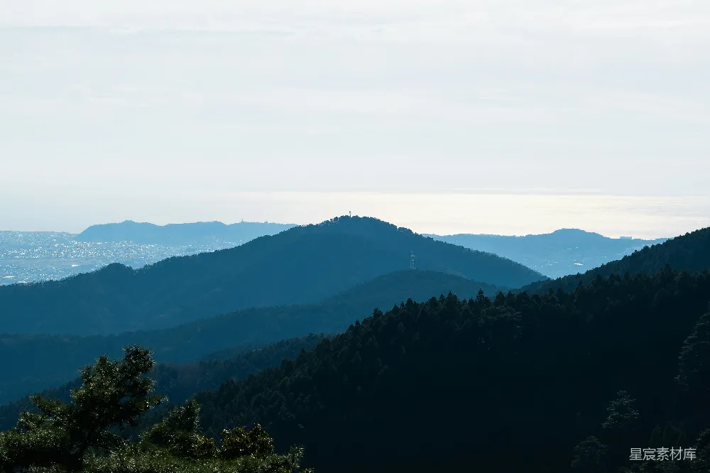 高清摄影  一片山峦景色，前景中有树木。