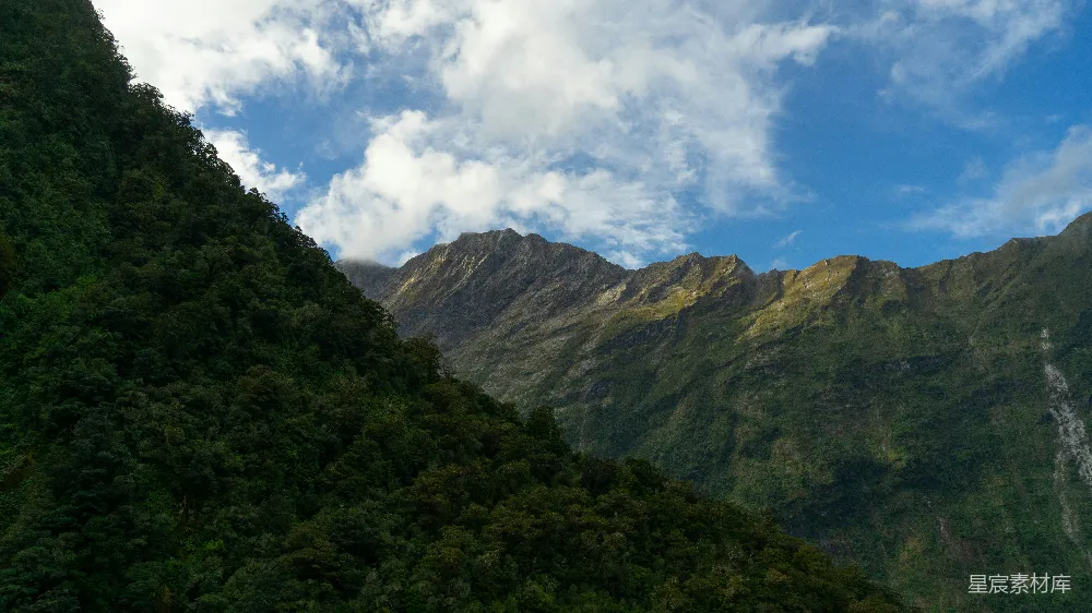 高清摄影  山峰在云层和蓝色的天空下耸立。