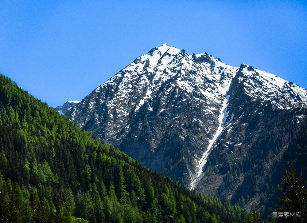 高清摄影 自然 白雪覆盖的山峰，绿树成荫的山坡。