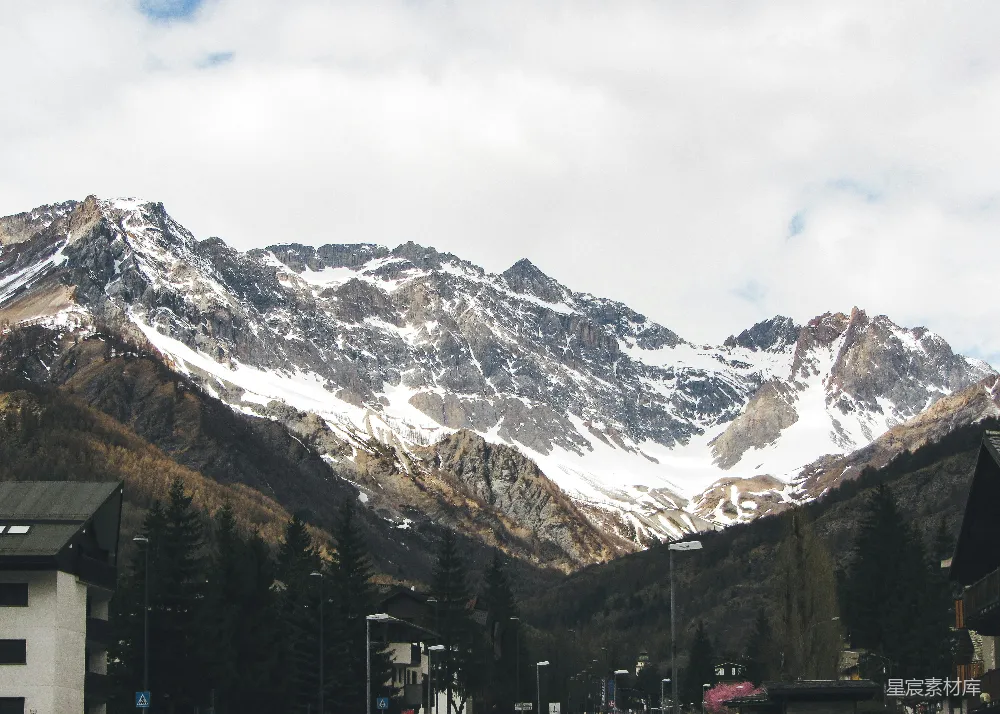高清摄影  白雪覆盖的山脉耸立在村舍之上。