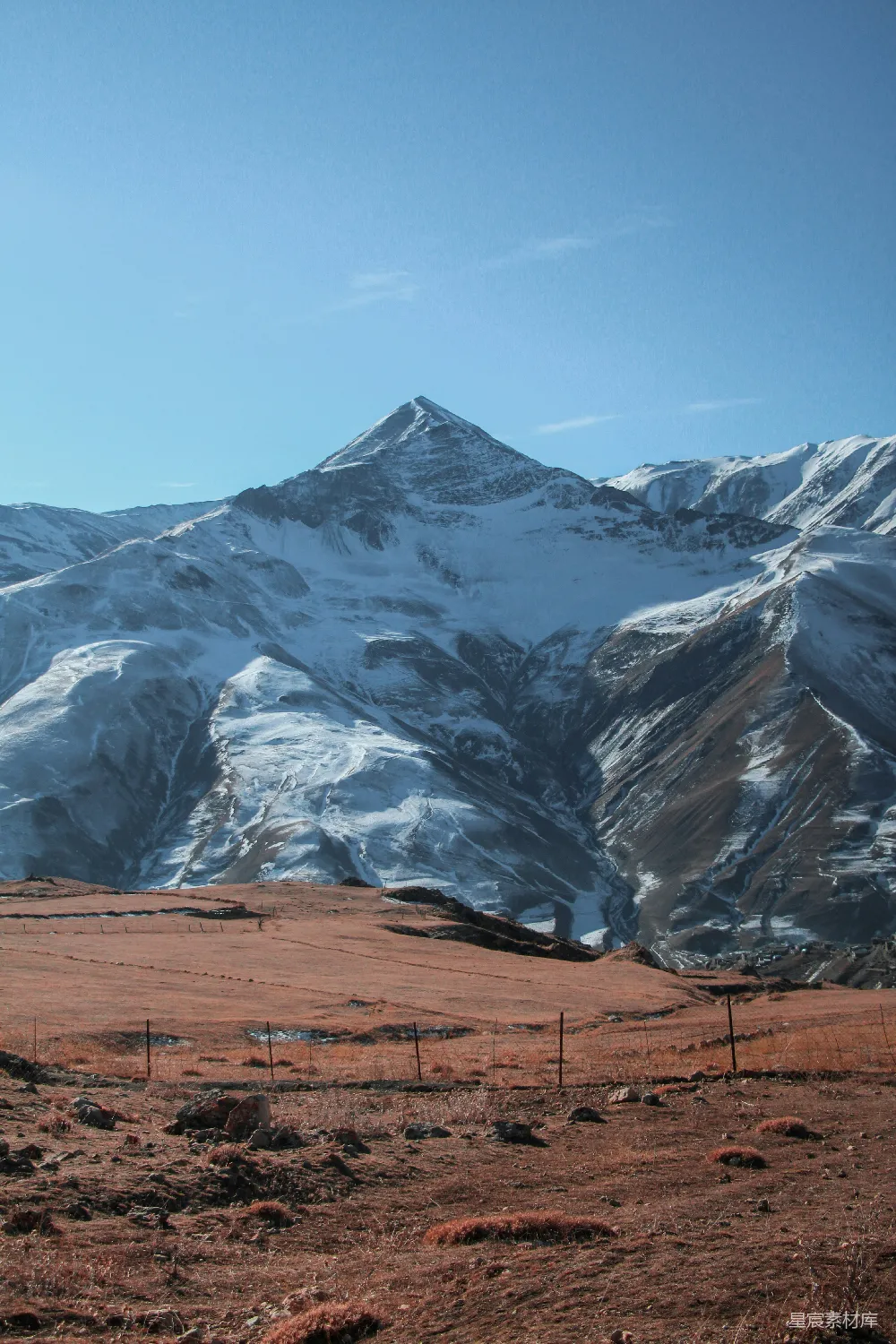 高清摄影  一座被雪覆盖的山脉，前景中有栅栏。