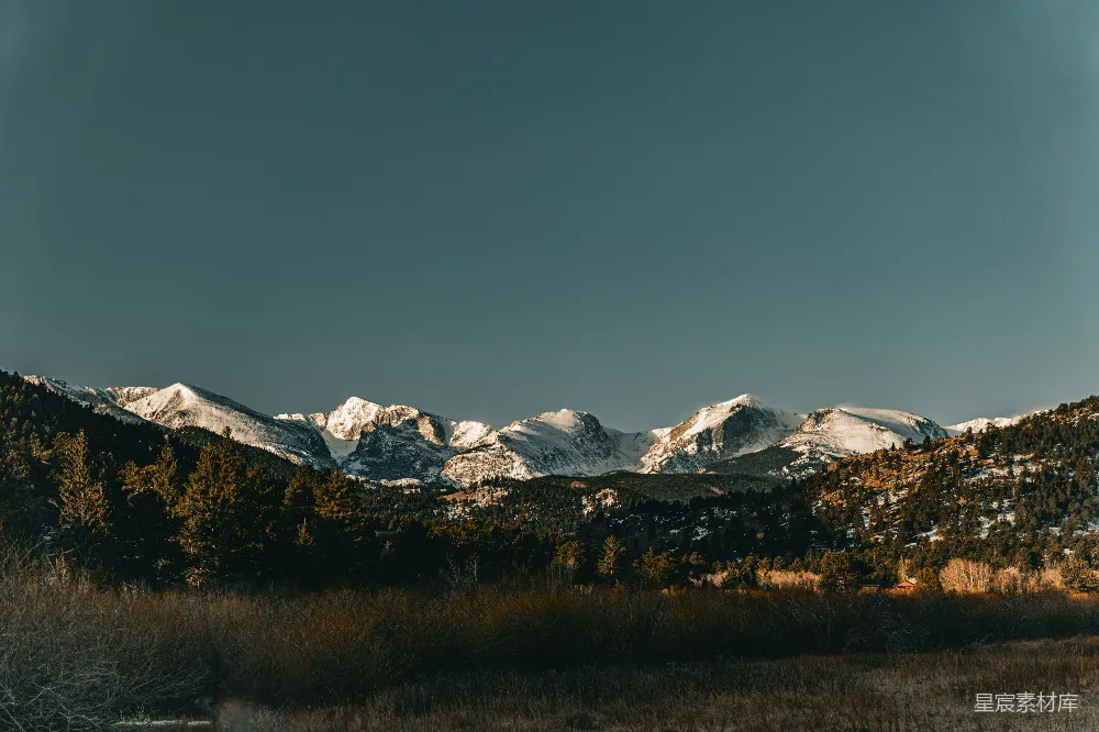 高清摄影  山峦被雪覆盖，草地呈现棕色。