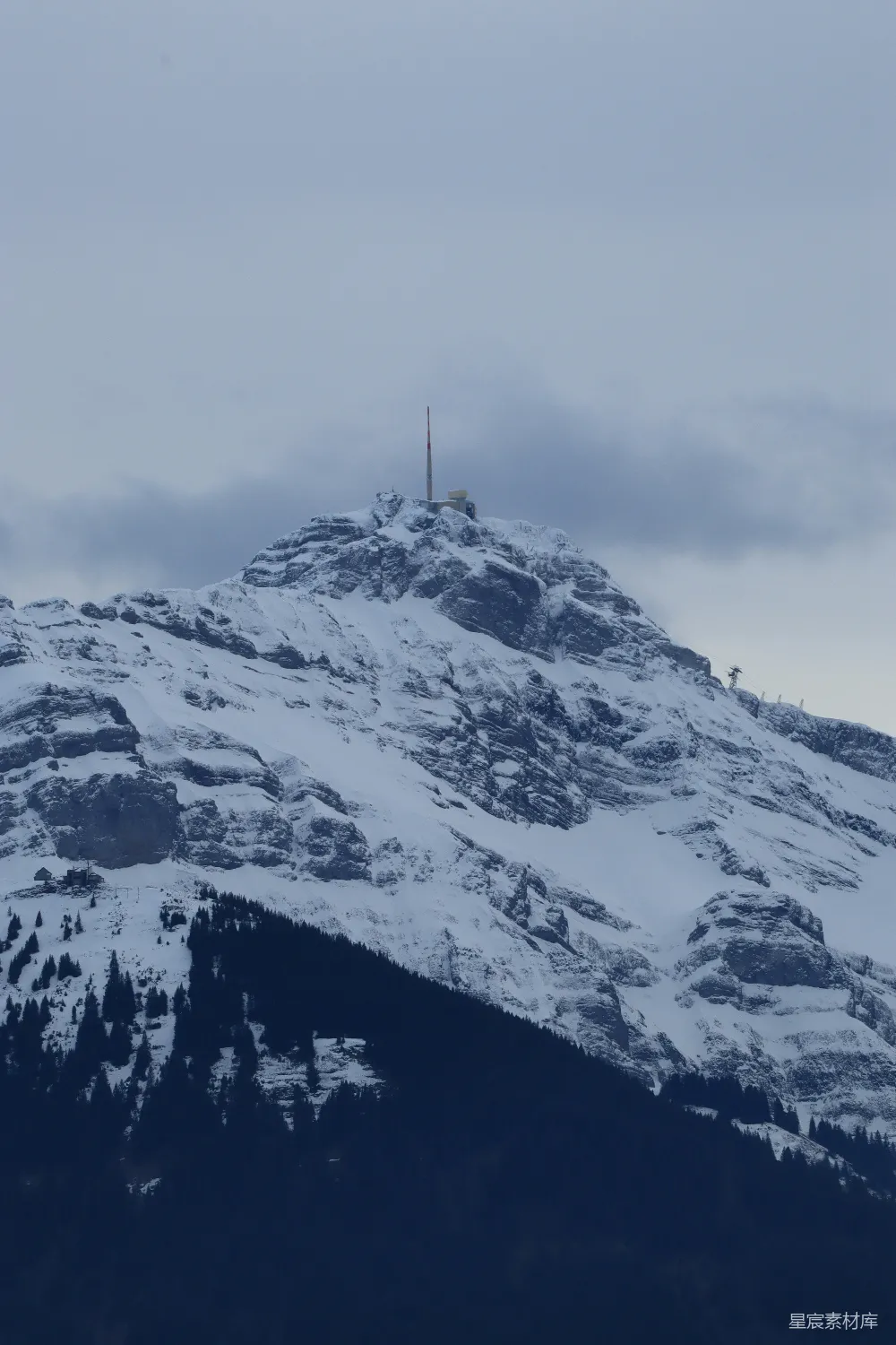 高清摄影  一座覆盖着积雪的山峰，山顶上有一座广播塔。