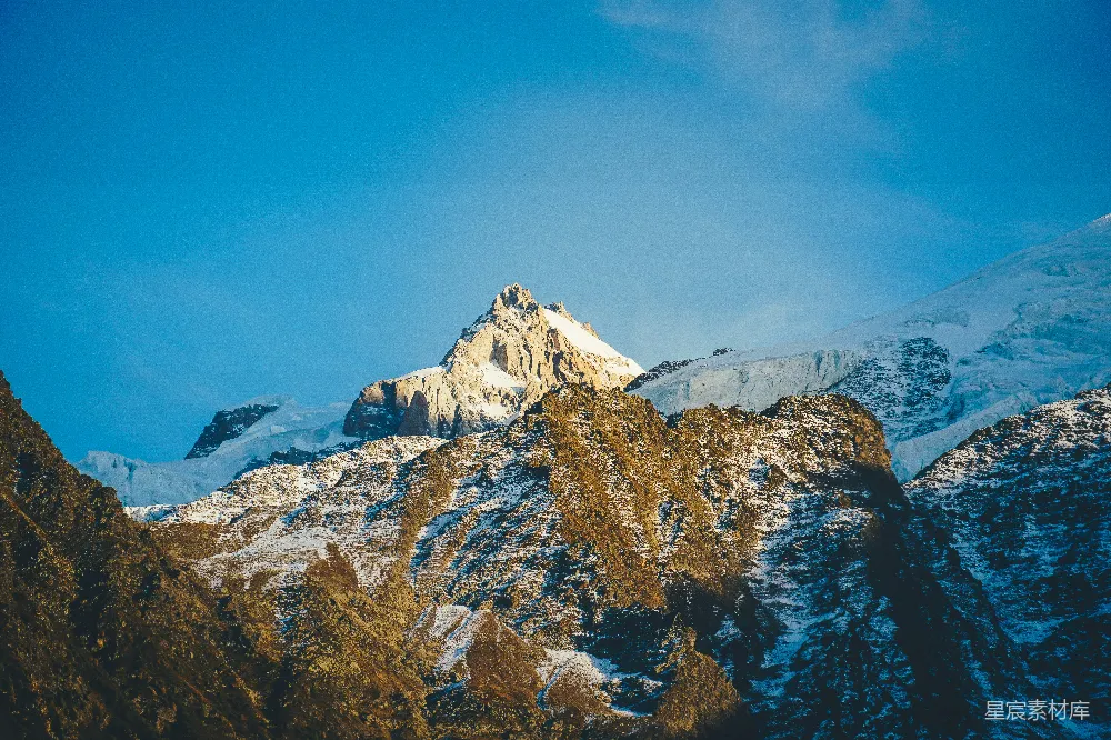高清摄影  一座覆盖着积雪的山峰，背景是蓝天。