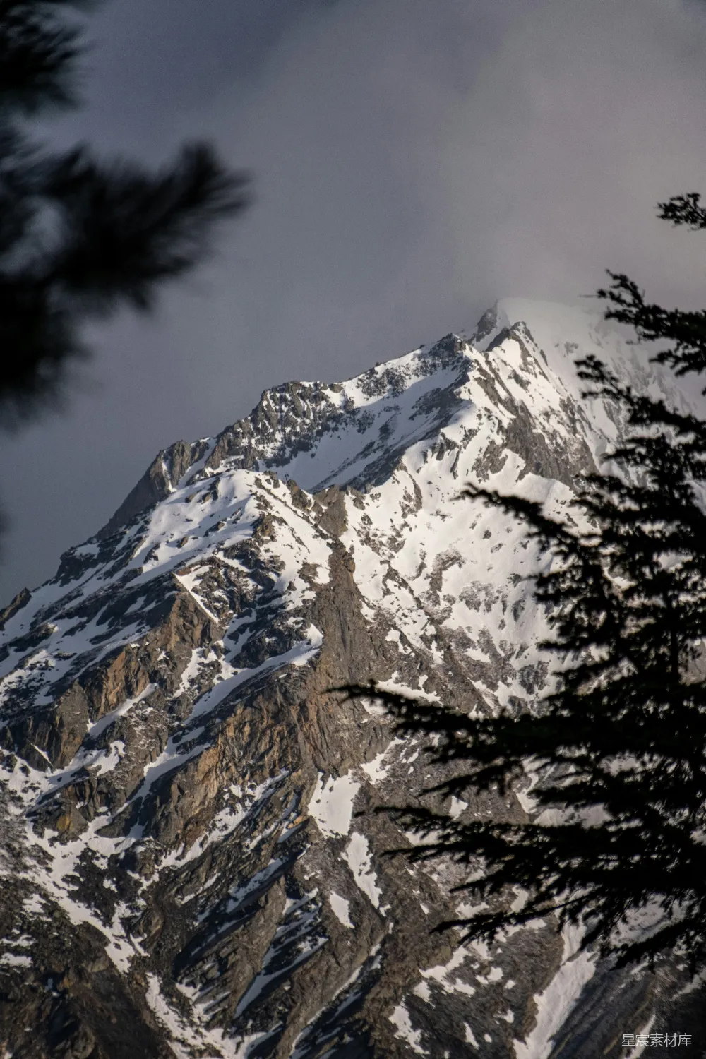 高清摄影  一座雄伟的雪山峰，在一片云层密布的天空下。