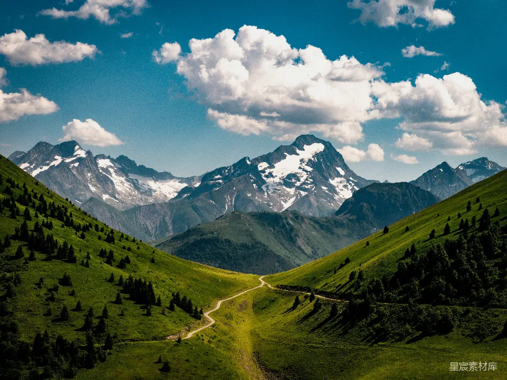 高清摄影  一条蜿蜒的山路穿过绿谷，通向雪山。