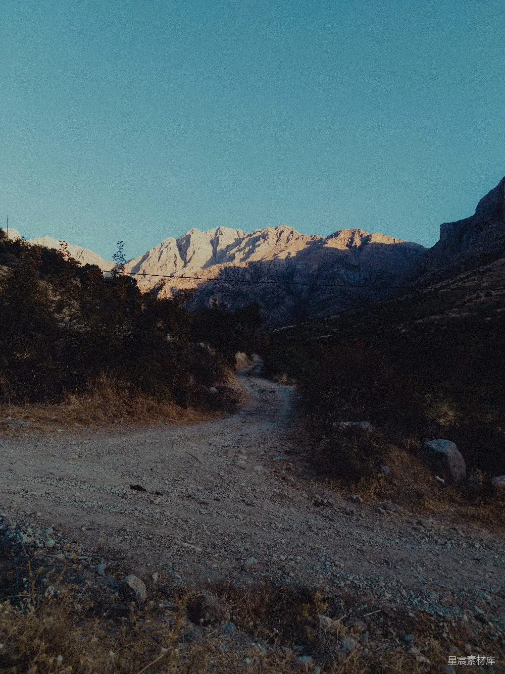高清摄影  一条泥土路，背景中有一座山。